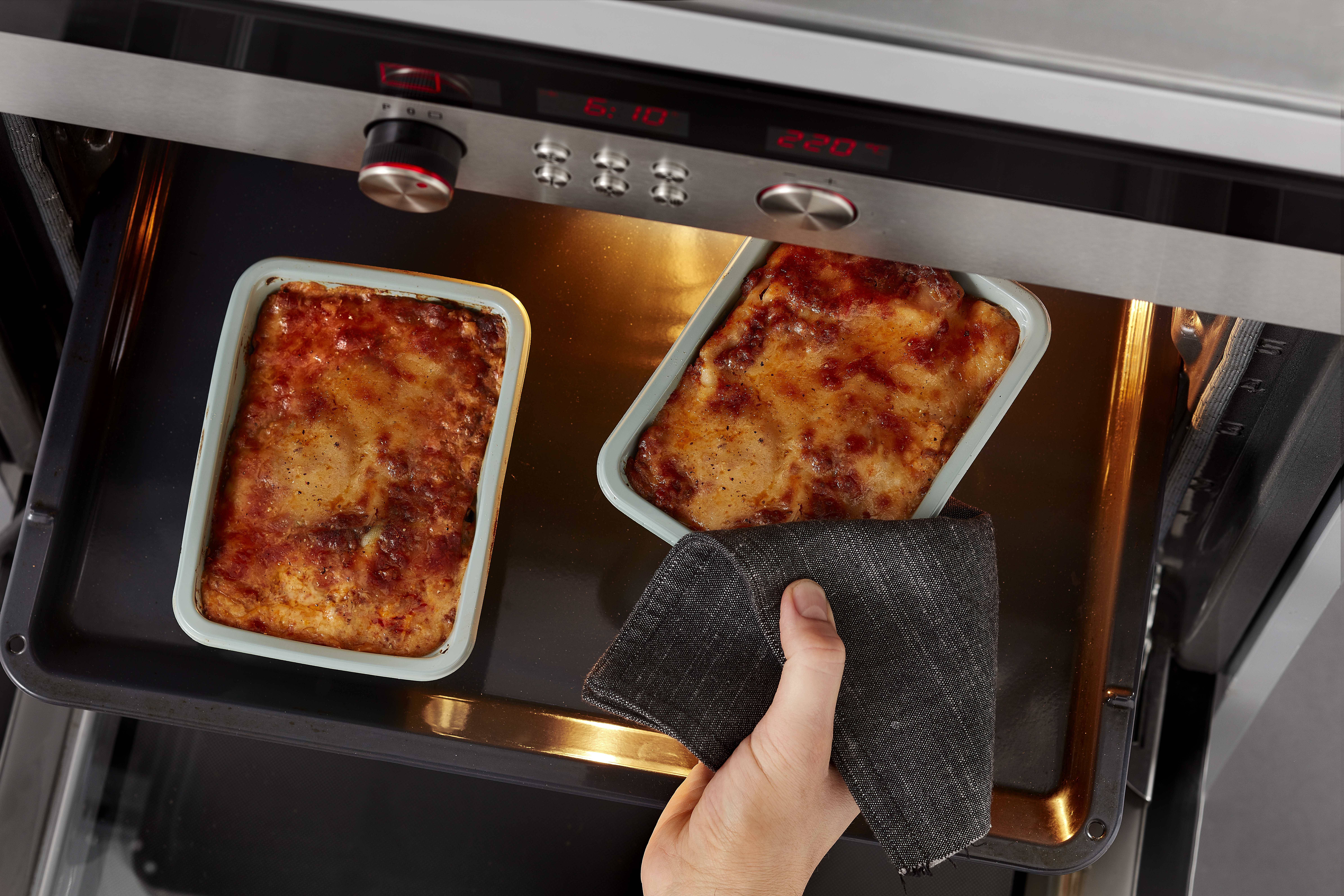 Green Evolve trays with lasagna in oven